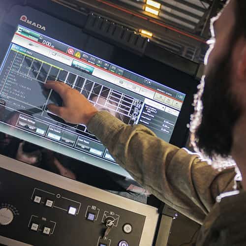 Camp employee working with an amada automated processing machine